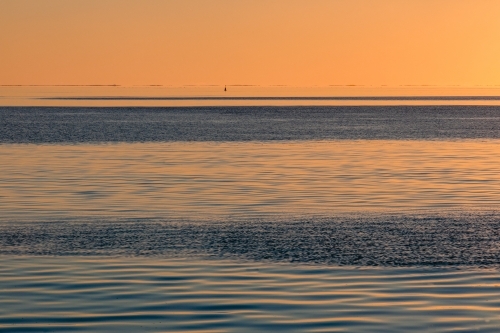 Water patterns on the calm ocean at sunset