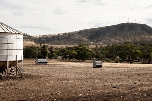 Water tank and feed bins in a dry paddock - Australian Stock Image