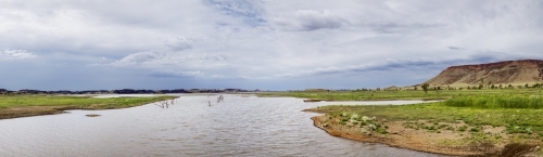 Waterway with distant hills and cloudy sky - Australian Stock Image