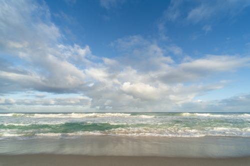 Waves breaking along beach shoreline under dynamic sky at Scarborough Beach, Perth - Australian Stock Image