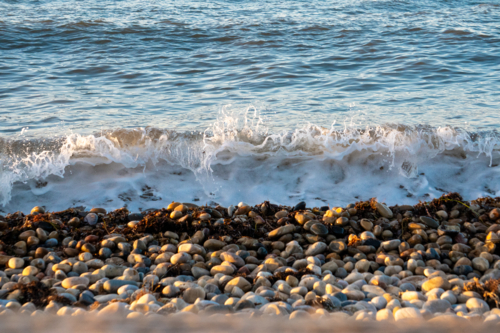 Waves crashing over pebbles - Australian Stock Image