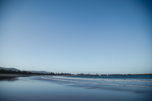Waves rolling in on Coffs Harbour Beach with jetty in the distance, NSW Australia - Australian Stock Image