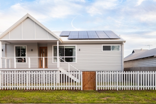 White house with picket fence and solar panels on roof - Australian Stock Image
