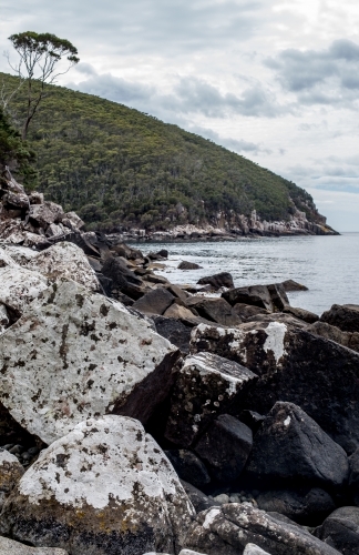 White lichen boulders lead our eye to a wooded peninsula - Australian Stock Image