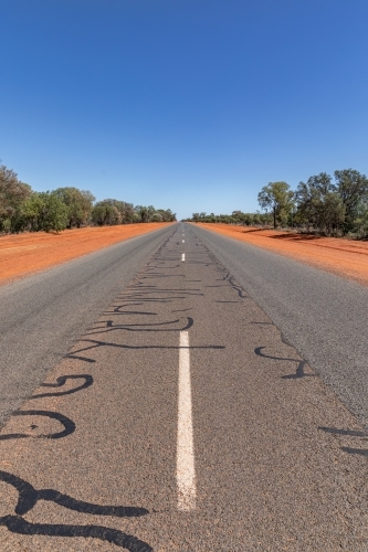 White lines down the middle of the road in Outback NSW with red dirt edges - Australian Stock Image