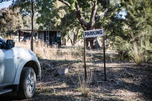 White parking sign near car in bush with trees - Australian Stock Image