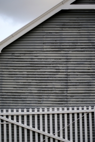 White picket fence leaning against a corrugated iron farm shed - Australian Stock Image