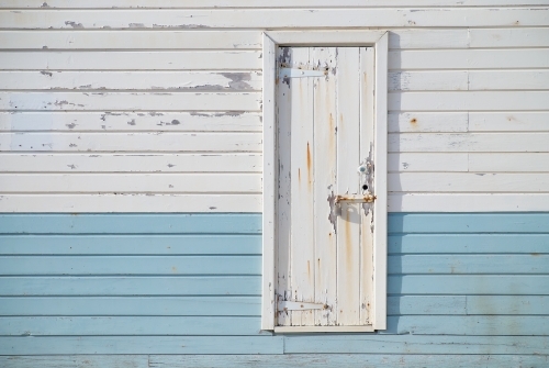 White rusting door on blue and white paneling on a port building.