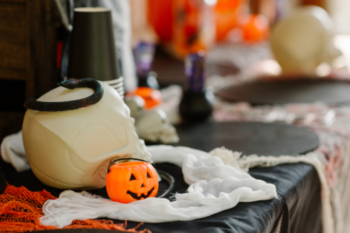 White skull with a coiled black snake resting on top, beside a small orange jack-o’-lantern bucket - Australian Stock Image