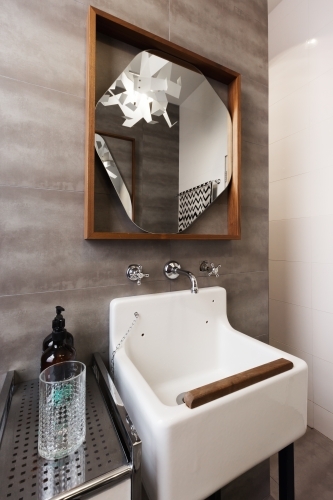 White vintage vanity basin with mirror against grey tiled wall