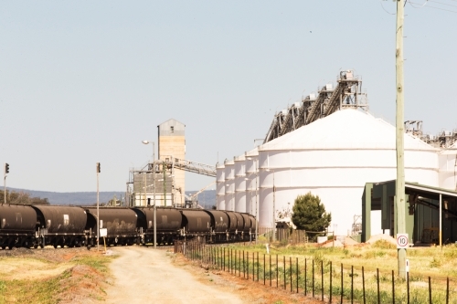 white warehouse and factories beside coal train track in the country side - Australian Stock Image