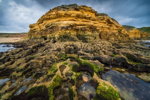 Wide angled view of rockpools below a rugged coastal headland under dramatic clouds