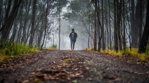 Wide shot of woman walking on foggy mountain track - Australian Stock Image