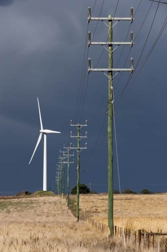 Wind turbine alongside power lines and fence - Australian Stock Image