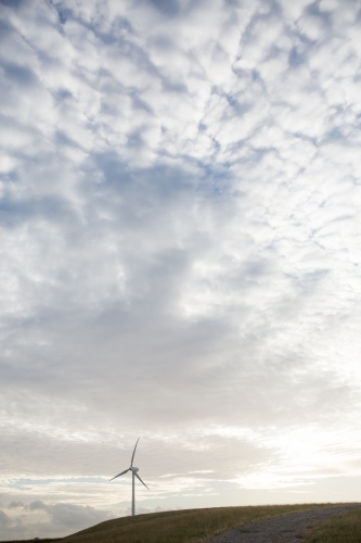 wind turbine on a hill with sun setting behind, room for copy - Australian Stock Image