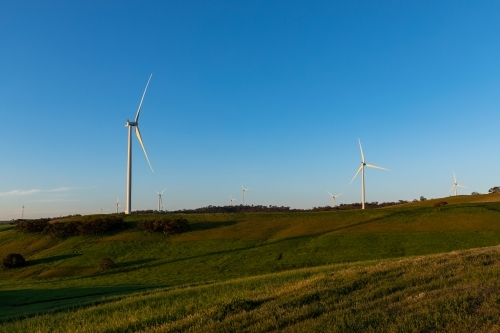wind turbines on hilltops against blue sky - Australian Stock Image