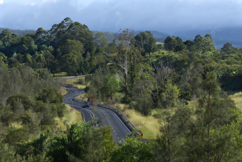 Winding country road, sun and clouds in distance - Australian Stock Image