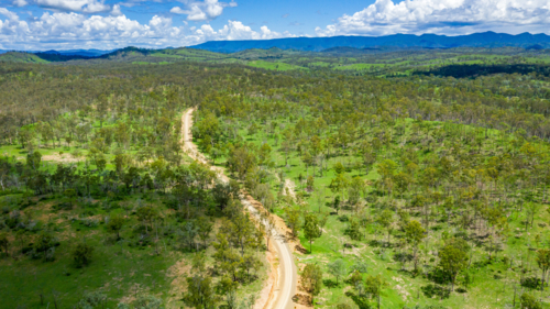 Winding dirt road through forested countryside and mountains - Australian Stock Image