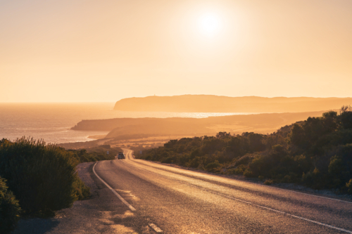 winding road across the Innes National Park with car at sunset time, Yorke Peninsula - Australian Stock Image