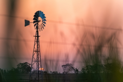 Windmill against a smoky sunset in drought conditions - Australian Stock Image