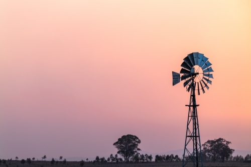Windmill against a smoky sunset in drought conditions - Australian Stock Image