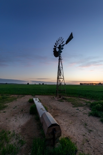 windmill and water trough at dusk - Australian Stock Image