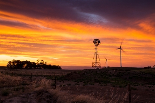 Windmill and wind turbines silhouetted against sunset - Australian Stock Image