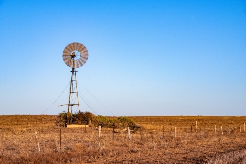 Windmill during the early morning in a dry empty Australian paddock. - Australian Stock Image