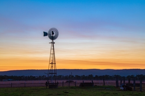 Windmill in the early dawn in a rural community - Australian Stock Image