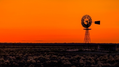 Windmill silhouette against an orange Sunset - Australian Stock Image