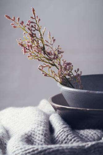 Winter still life of grey bowls, scarf and flowers vertical