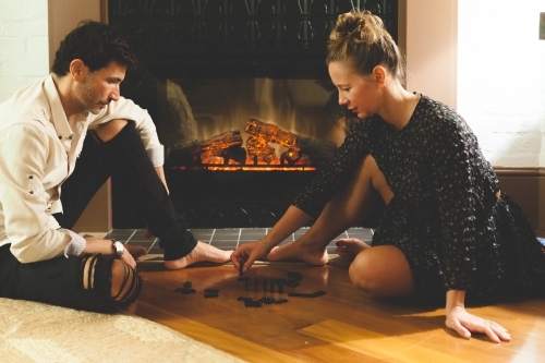 Woman and man playing dominoes by the fireplace
