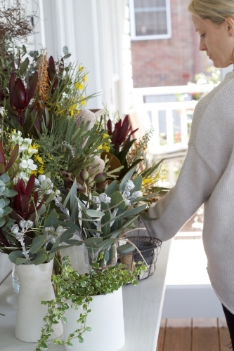 Woman arranging flowers on table - Australian Stock Image