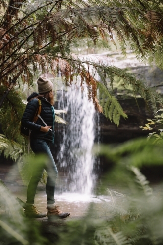 Woman bushwalking towards a waterfall in the rainforest