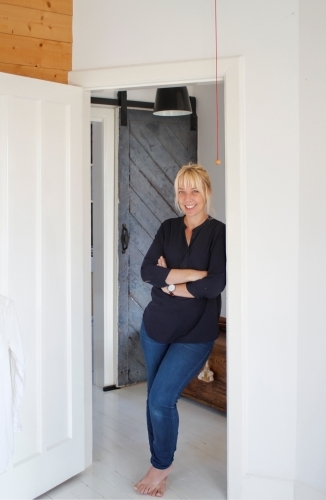 Woman casually leaning against doorway in white walled home - Australian Stock Image