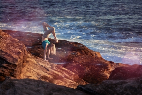 Woman doing yoga by the ocean - Australian Stock Image