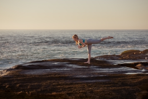 Woman doing yoga by the ocean - Australian Stock Image