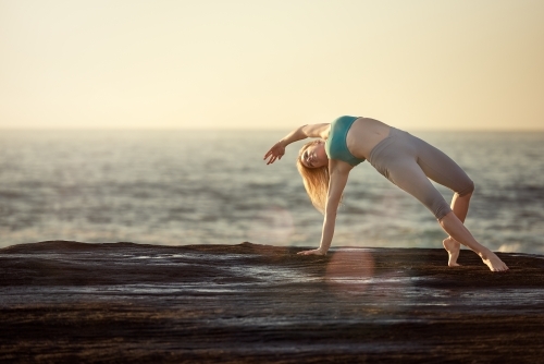 Woman doing yoga by the ocean - Australian Stock Image