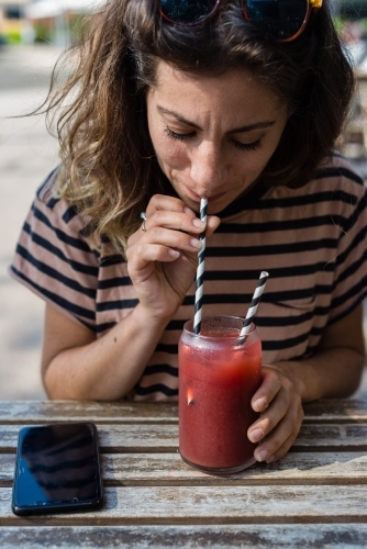 woman drinking fruit drink in a cafe - Australian Stock Image