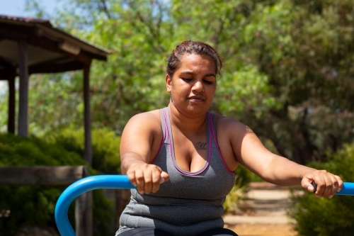 woman exercising outdoors on community fitness equipment - Australian Stock Image