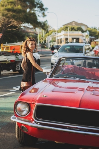 woman getting into classic car parked on the street - Australian Stock Image