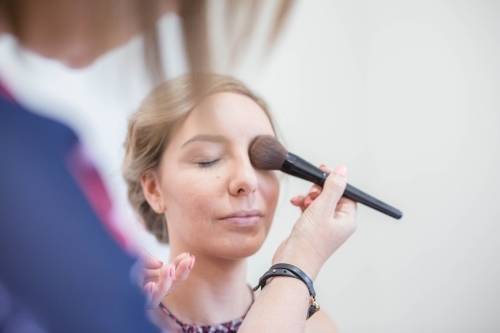 Woman having makeup put on with brush