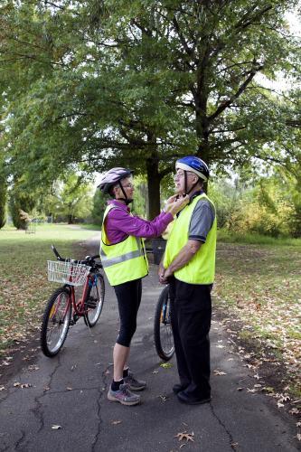 Woman helping disabled man with bike helmet - Australian Stock Image