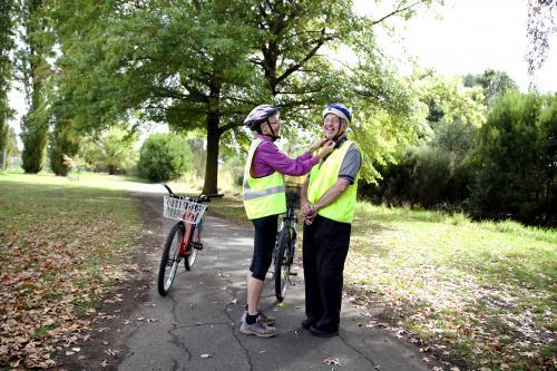 Woman helping disabled man with cycling helmet - Australian Stock Image