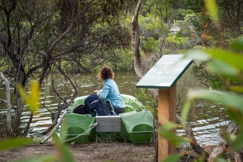 Woman hiking Kangaroo Island Wilderness Trail sitting in boat - Australian Stock Image