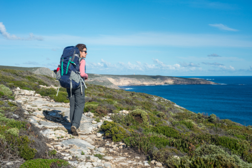 Woman hiking Kangaroo Island Wilderness Trail with backpack near ocean - Australian Stock Image