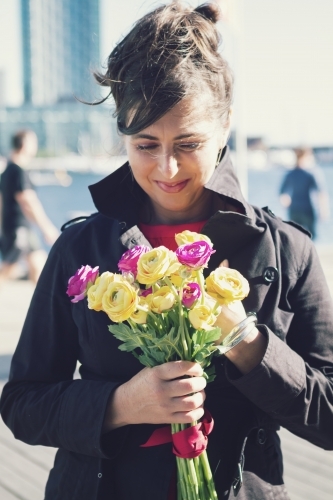 Woman holding a bunch of purple and yellow roses on Docklands promenade - Australian Stock Image