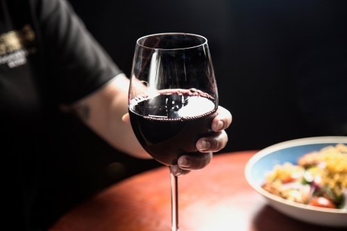 Woman holding a glass of red wine - Australian Stock Image