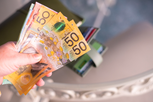 woman holding Australian money, with wallet on the table in the background - Australian Stock Image