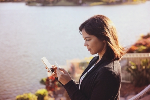 Woman holding credit card and mobile by the lake, online shopping, internet banking concept - Australian Stock Image